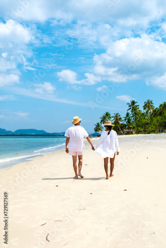 Koh Mook a young couple of caucasian men and Thai Asian woman walking at the beach in Thailand © Fokke Baarssen