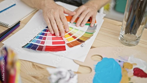 Man examining color swatches in a creative studio environment, suggesting design, art, or decoration planning. photo
