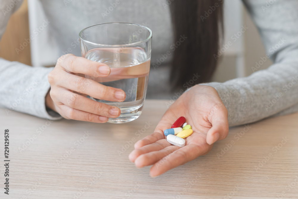 Sick, asian young woman, girl hand holding pill capsule, painkiller medicine from stomach pain, headache, pain for treatment, take drug or vitamin and glass of water at home, pharmacy and health care Sick, asian young woman, girl hand holding pill capsule, painkiller medicine from stomach pain, headache, pain for treatment, take drug or vitamin and glass of water at home, pharmacy and health care