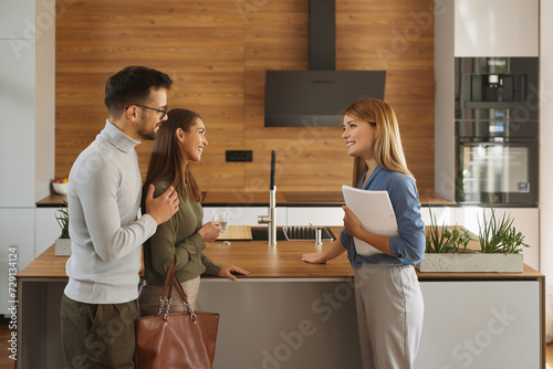 Female shop assistant helping young couple choose new kitchen appliance photo