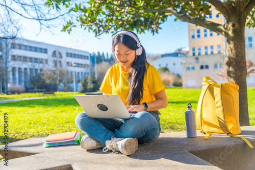 Chinese woman using laptop sitting outside the campus