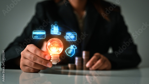 Business man hand holding glowing light bulb with virtual hologram. Investment and business Innovation ideas concept