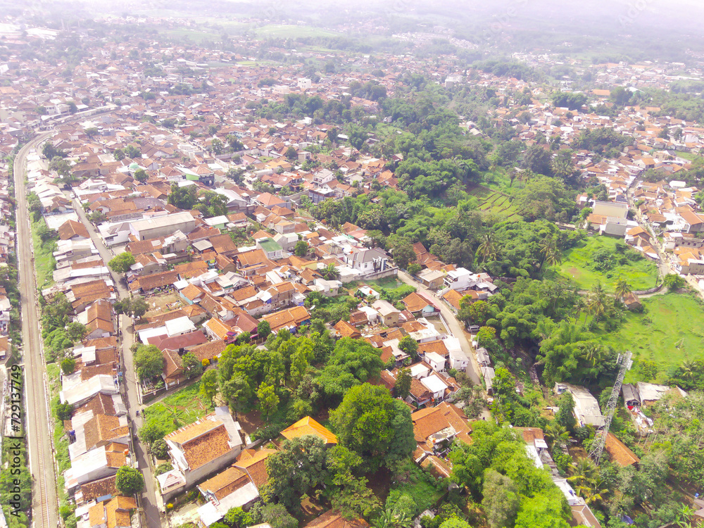 Aerial View of Nagreg City - Indonesia from the Sky. There are rice fields, valleys and hills, squeezed by dense settlements and a main road. Shot from a drone flying 200 meters high.