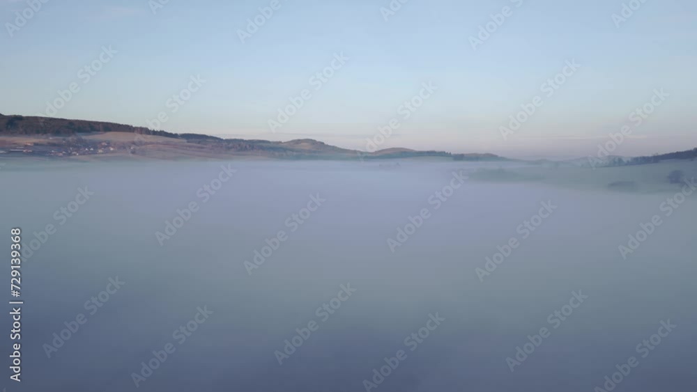 Tranquil scene of rolling hills emerging above a vast expanse of fog under a sky transitioning from night to dawn Tranquil scene of rolling hills emerging above a vast expanse of fog under a sky transitioning from night to dawn