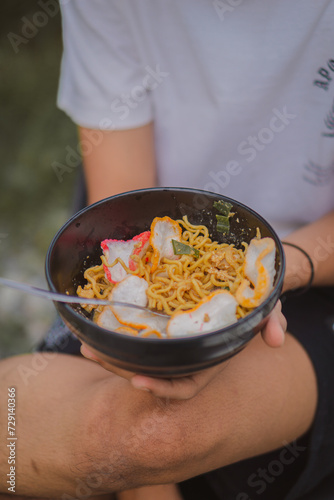 Person holding a bowl of noodle