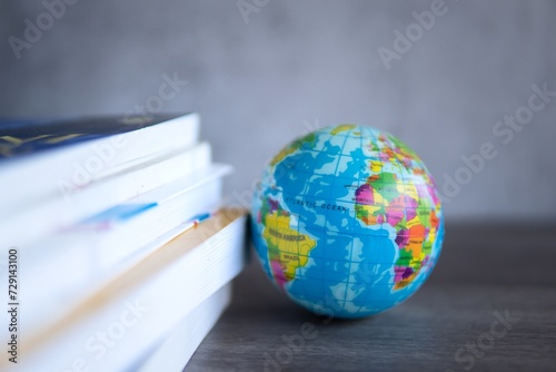 Closeup image stack of books with a globe on a wooden table. Copy space for text. World book day, education and knowledge concept.