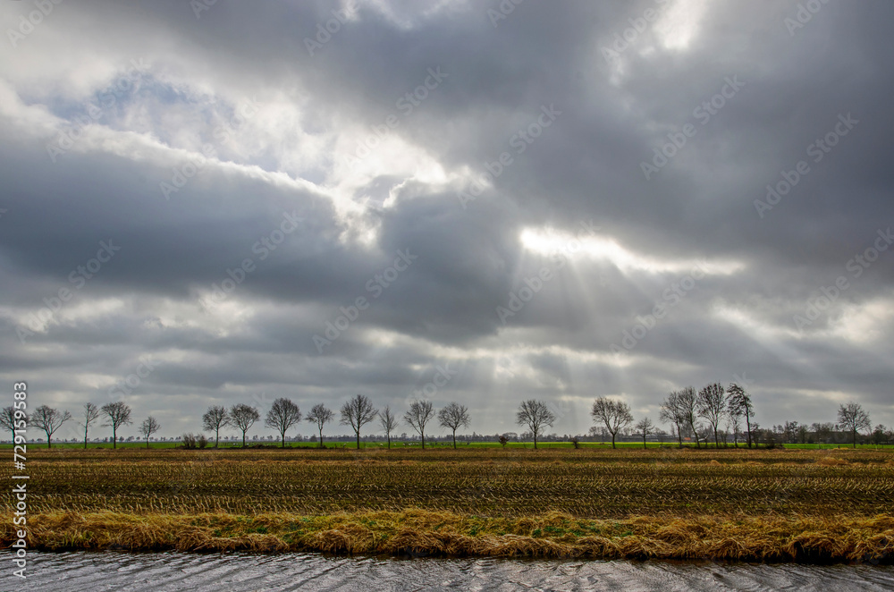 Spectacular sky with dramatic clouds and rays of sunlight over a polder landscape near Schoonhoven, The Netherlands