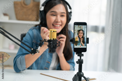 Host channel Asian influencer talking in broadcast wearing headsets on social media live on smartphone recording online, greeting listeners with coaching life or business at modern studio. Stratagem.