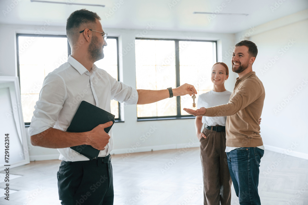 Giving the keys. Realtor shows an apartment to a young couple Giving the keys. Realtor shows an apartment to a young couple