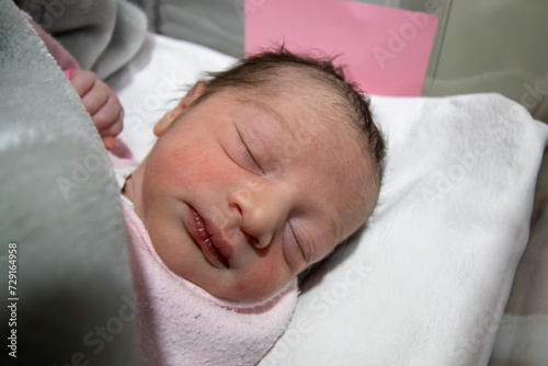 On her first day of life, a newborn baby girl wears a pink hospital ID bracelet on her hand photo