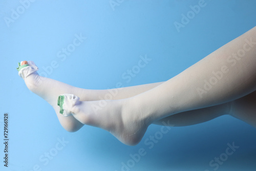 Woman with lateral view of the legs wearing medical compression socks in a light blue background  photo