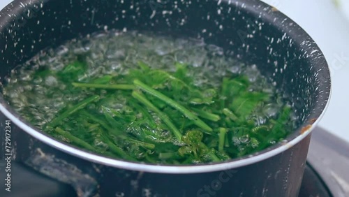 Ambient motion of wild edible fiddlehead ferns or Diplazium esculentum blanching in boiling water to make pako salad, an authentic Filipino local delicacy