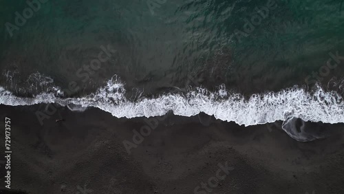 Waves breaking on black sand beach, Plage de Grande Anse bay, Guadeloupe, French Antilles. Aerial top-down sideways and space for copy photo