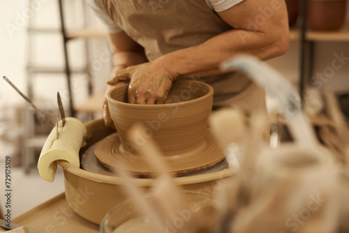 Potter turning a bowl on a wheel in a ceramic studio