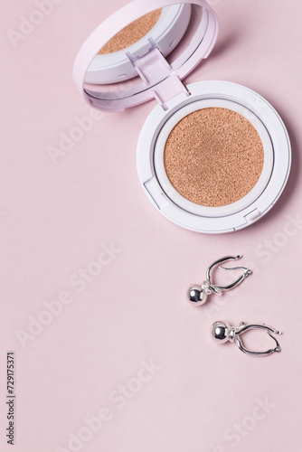 Powder Cushion for makeup and earrings on a Pink Background Makeup Products and Bijouterie Vertical Background Copy Space