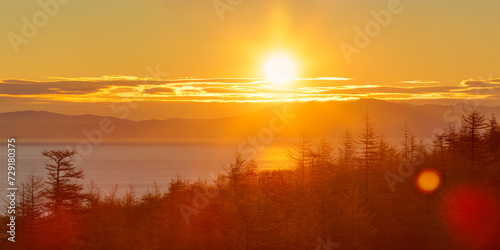 Morning landscape. Sunrise over the sea bay. Larch forest on the coast. Rising sun over the mountains. Autumn panorama. Nature of Siberia and the Russian Far East. Travel in the Magadan region. Russia