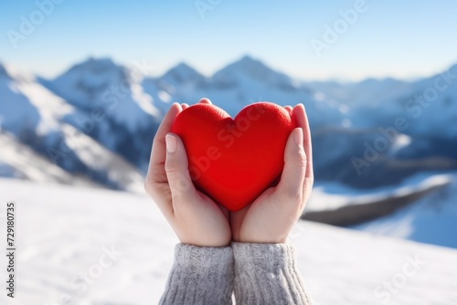 Red heart in womans hands at the snowy mountains background.Travel and Honeymoon Promotions concept Wellness and Relaxation Campaigns concept Relationship and Dating Apps concept.