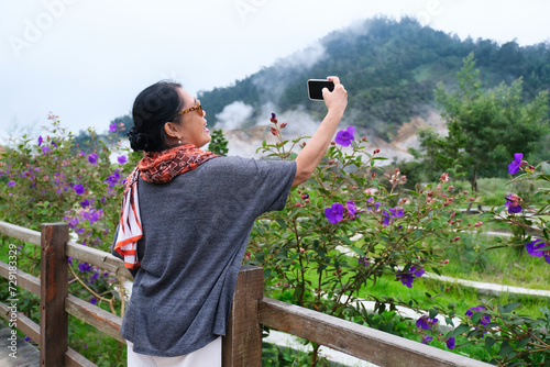 A middle-aged woman is taking a selfie in a park photo