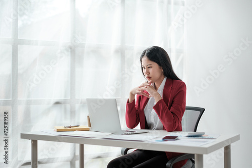 Portrait of beautiful business asian woman in red suit working office desk computer. Small business sme . © Treerat