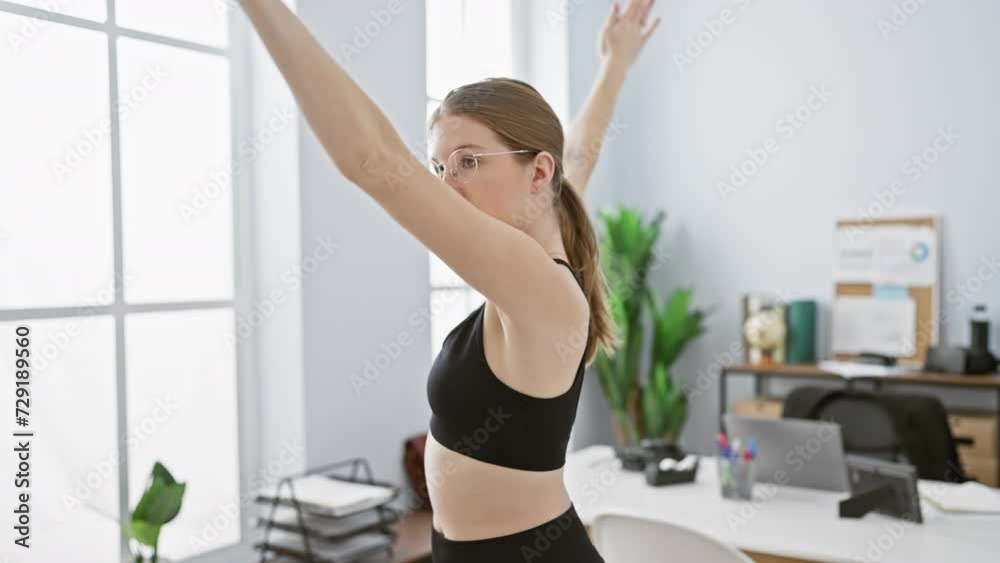 A young woman in activewear stretching in a modern office environment, indicating a workplace wellness or break time concept. A young woman in activewear stretching in a modern office environment, indicating a workplace wellness or break time concept.