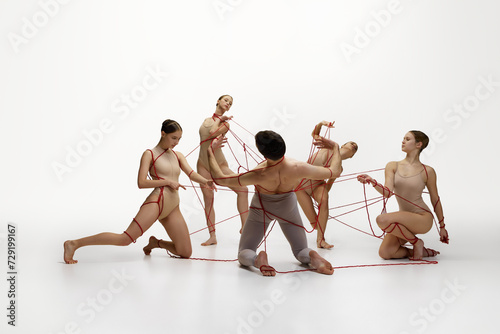 Maintenance of social life. Ballet dancers connected with red stings performing against white studio background. Social ties. Concept of classical dance, modern style, inspiration
