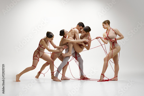 Protection of private life and personal affection. Ballet dancers connected with red strings performing against white studio background. Concept of classical dance, modern style, inspiration