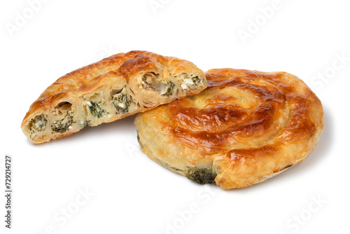 Whole and halved fresh baked Turkish borek with spinach and cheese close up isolated on white background
