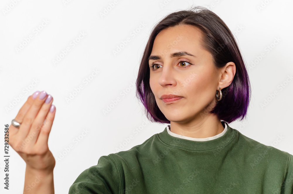 Dark-haired woman seems to be holding mirror in her hand and looking into it. White background.