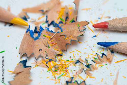 Color watercolor pencils with shavings close up on a white background.