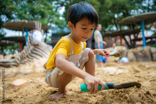 Asian kid boy 5 year old enjoying play outdoor sandbox having fun on playground in sandpit.
