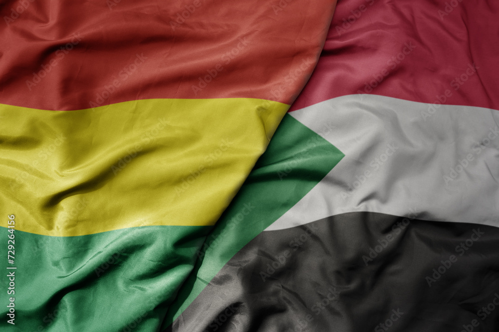 big waving national colorful flag of sudan and national flag of bolivia . big waving national colorful flag of sudan and national flag of bolivia .