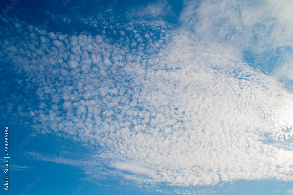 Blue sky with white altocumulus clouds. Background on the theme of weather and ecology. Blue sky with white altocumulus clouds. Background on the theme of weather and ecology.