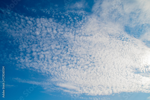 Blue sky with white altocumulus clouds. Background on the theme of weather and ecology.