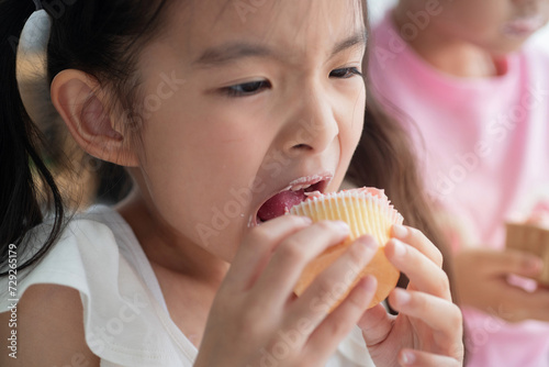 Cute little girl eats cupcakes until her lips are smeared with cream  good times with holiday activities at home with family