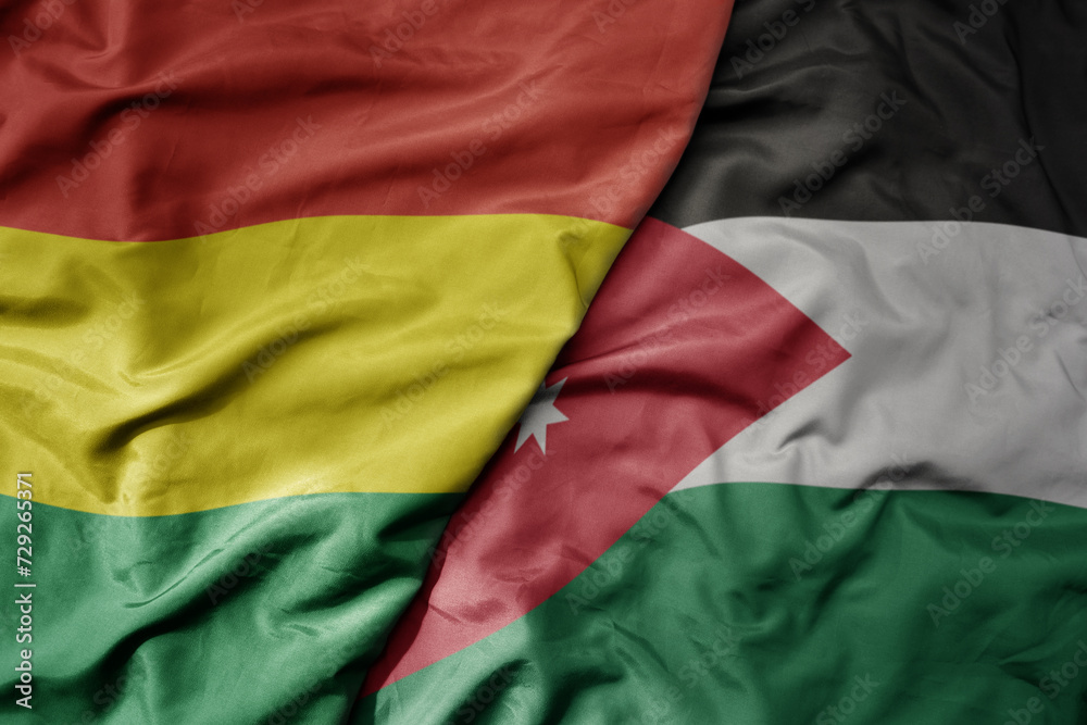 big waving national colorful flag of jordan and national flag of bolivia .