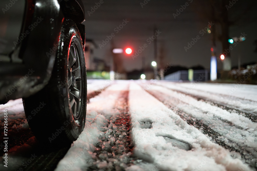 雪の積もった交差点と車のタイヤ