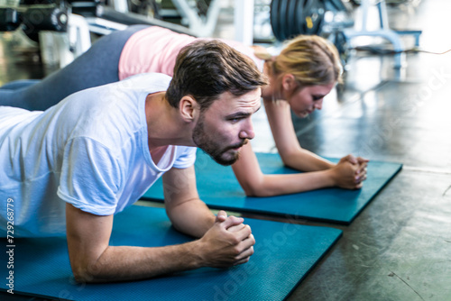 Sport active caucasian man and woman friend doing plank position indoor sport gym