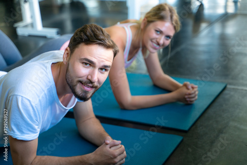 Sport active caucasian man and woman friend doing plank position indoor sport gym