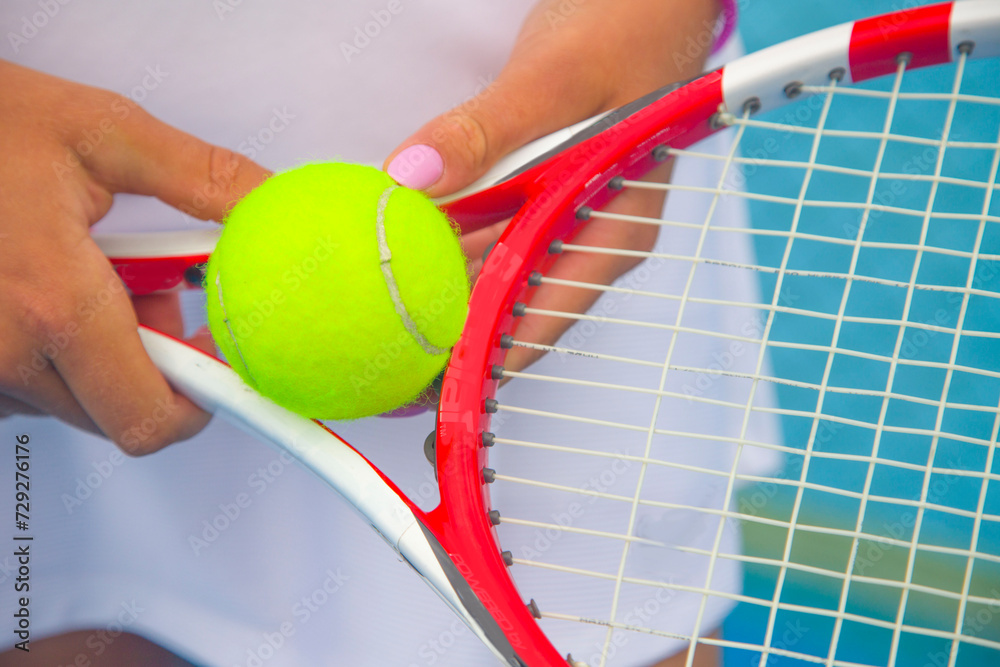 close-up of the hands of a female tennis player holding a tennis racket and a tennis ball