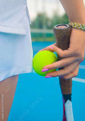 close-up of the hands of a female tennis player holding a tennis racket and a tennis ball
