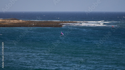 Windsurfing. Windsurfers playing with the waves in Caleta Famara, on the island of Lanzarote (Spain)