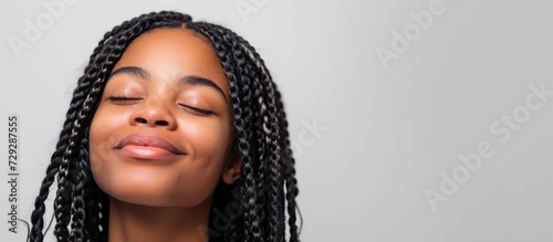 African American girl with braided hair, smiling and showing gratitude, over a plain background.