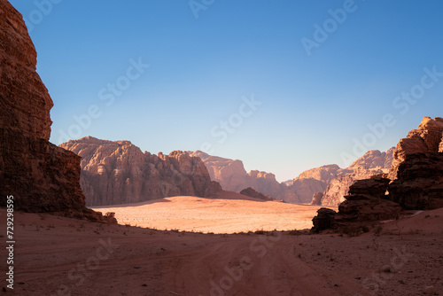 Wadi Rum, Jordan, Scenic view of Arabic Middle Eastern desert against clear blue sky with sand tracks in foreground. Mountain in background. Copy space no people. Landscape horizontal