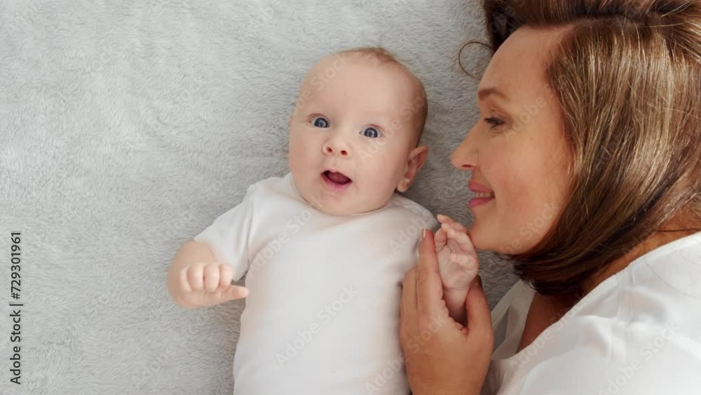 Happy newborn baby with his mother. Healthy newborn baby in a white t-shirt with mom. Closeup Faces of the mother and infant baby. Cute Infant boy and parent, top view. Slow motion. Happy family Happy newborn baby with his mother. Healthy newborn baby in a white t-shirt with mom. Closeup Faces of the mother and infant baby. Cute Infant boy and parent, top view. Slow motion. Happy family
