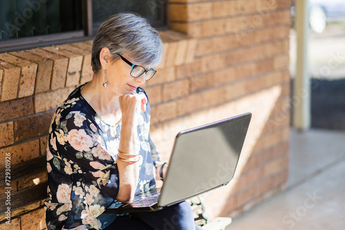 woman working on laptop outside thinking photo