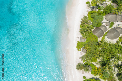 Aerial Maldives landscape view tropical summer palm trees sandy coast ocean waves splash crash. Beautiful sunny sea exotic resort amazing nature landscape. Drone view of tourism beach villas bungalows