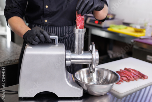 Cooking minced pork and beef by passing it through a electric meat grinder in the restaurant kitchen. photo