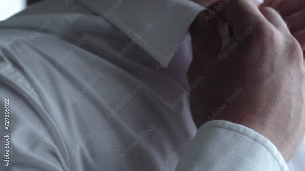 a man buttons up the white shirt of his business blue suit, a wedding suit, a business smart guy groom