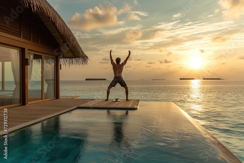 Man doing yoga on the terrace of a traditional luxury bungalow in Maldive islands at sunrise. 