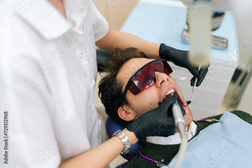 Quadro su tela Female dentist using modern diode dental laser for periodontal care, top view
